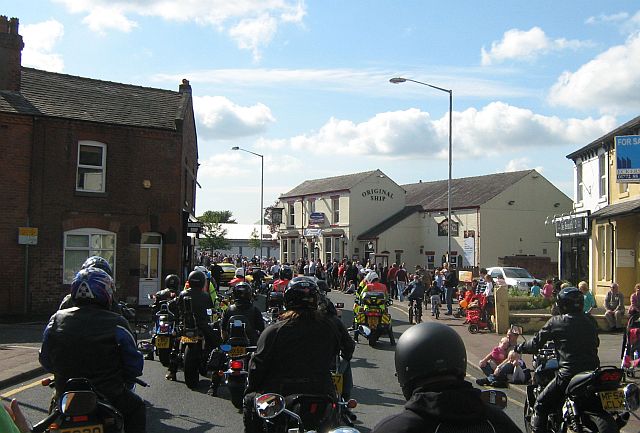 a large parade of motorcycles and riders riding in the sunshine