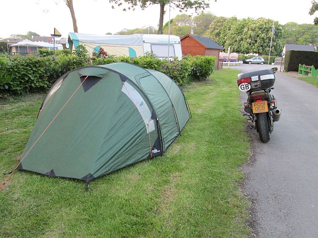 the tent on a small grass area next to the motorcycle