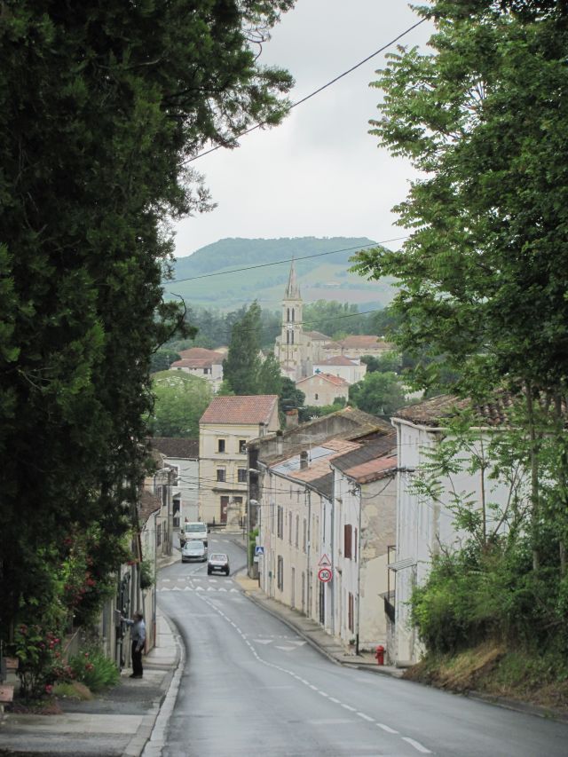 a typical french street in penne d'agenais with houses and trees