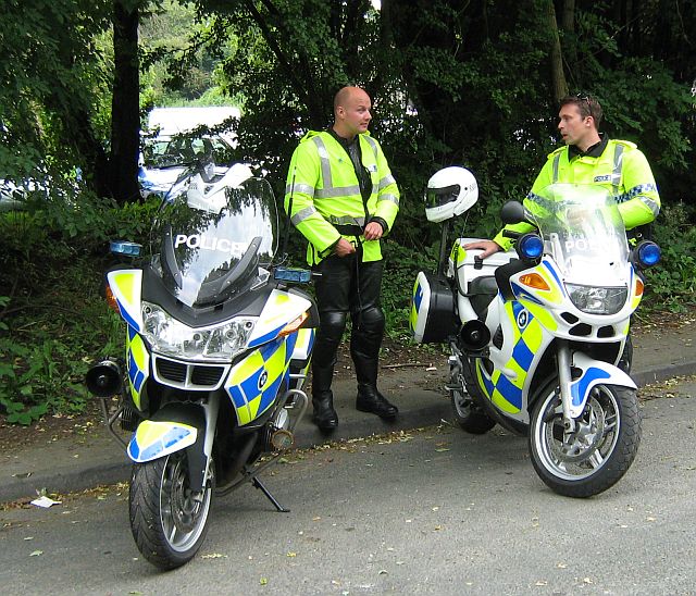 2 police motorcycle riders next to their police bikes