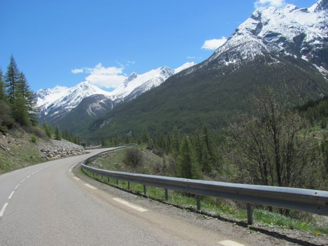 A road twists and turns through snow capped alpine mountains