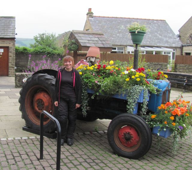 sharon stands smiling next to a tractor covered in flowers at chipping in the trough of bowland