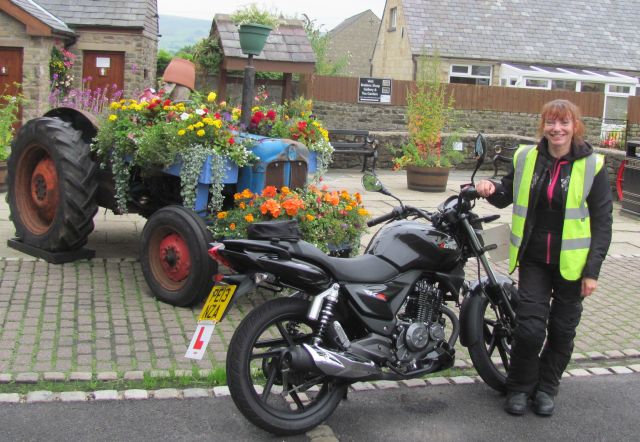 sharon stood by her learner motorcycle in the pretty village of chipping