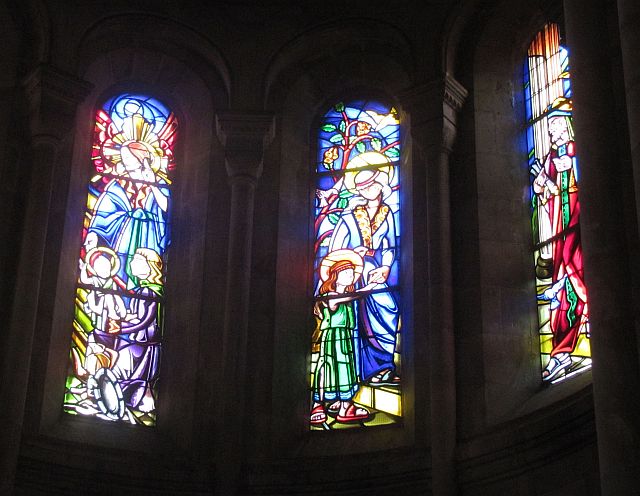 3 tall arched stained glass windows with the light shining through