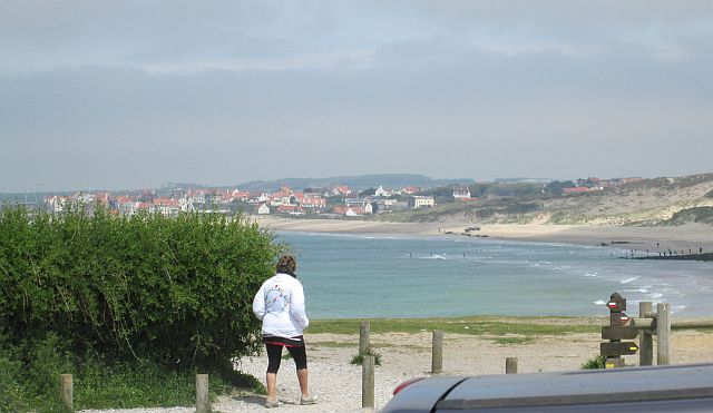 a broad sandy bay with the town of wimeraux in the background