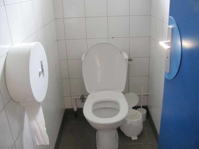 toilet in a small white tiled cubicle