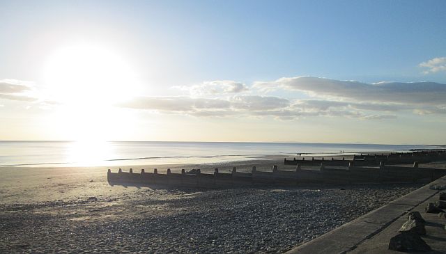 a bright sunset over a shadowy beach at tywyn mid wales