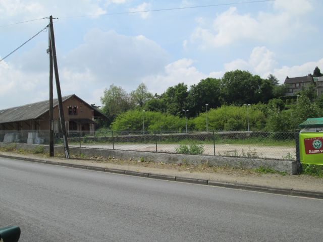 a dull industrial building and gravelly weedy empty area in france