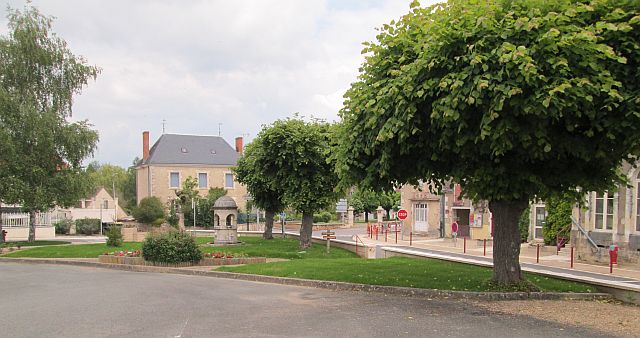 trees and crisp french style houses around a garden village green in france