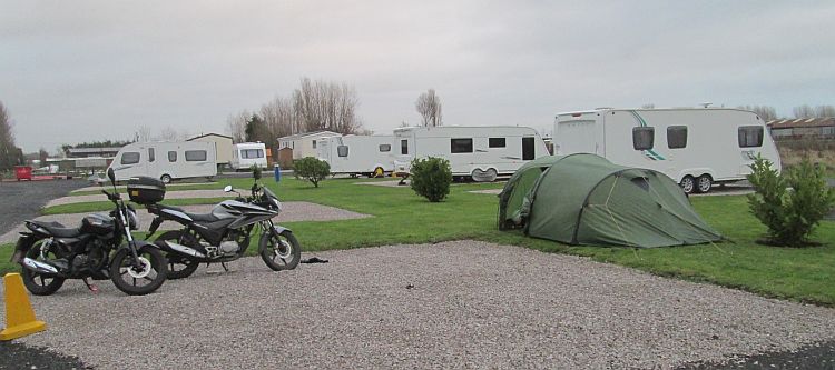 the 125 parked on gravel by the tent at the campsite near blackpool