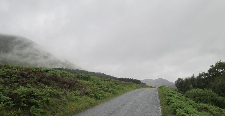 mist rolls across a highland hillside on a lonely empty lane