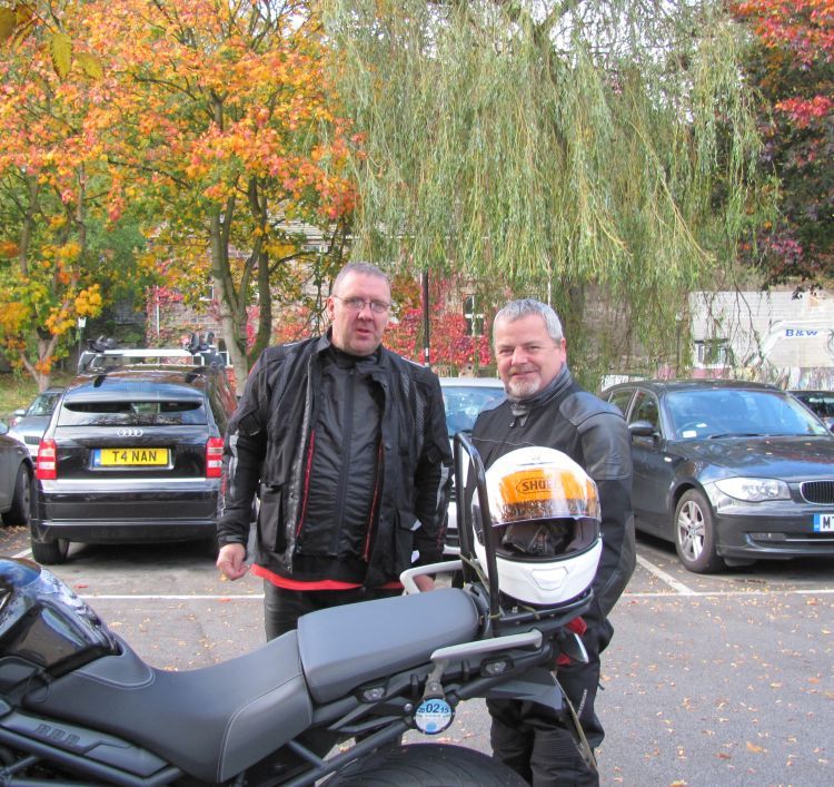 2 motorcyclists stand among the autumnal trees at hebden bridge