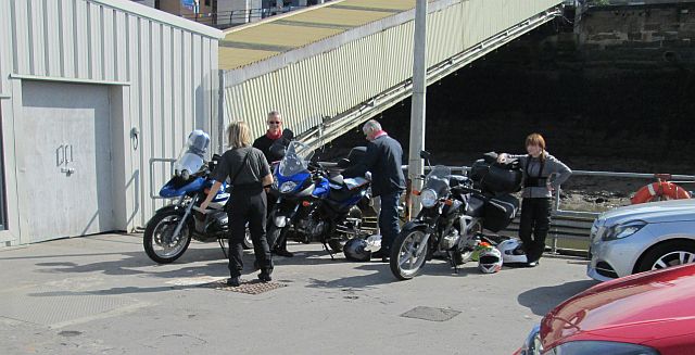 3 motorcycles and their passengers waiting in the sun for the isle of man ferry
