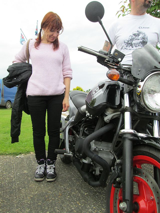 the gf stands next to a small sexy buell 500cc single motorcycle
