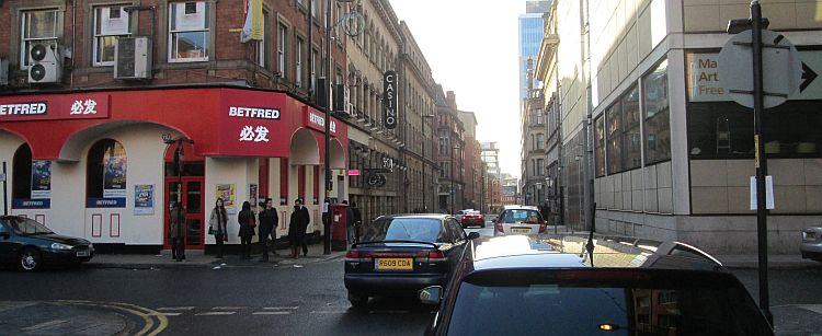 a handful of people and parked cars in manchester's chinatown