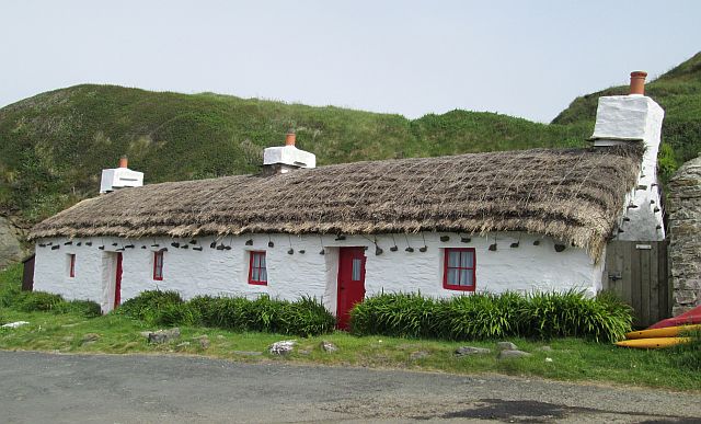 a long small low thatched building set against the hills at niarbyl