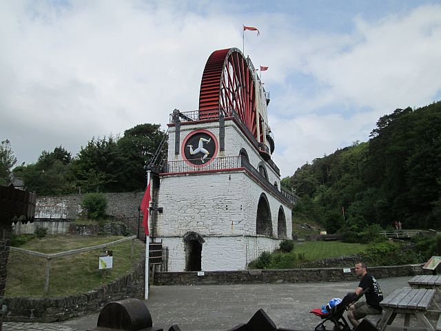 the laxey wheel, a tall steel water wheel painted bright red on a white masonry plinth.