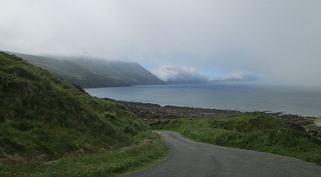a narrow land heads downhill with misty hills running to the sea at niarbyl