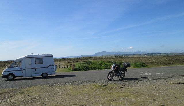 campervan and the cbf 250 on a vast dusty flatland and mountains in the distance at point of ayre