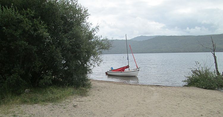 a small sandy beach runs into loch rannoch complete with tiny sailing dinghy