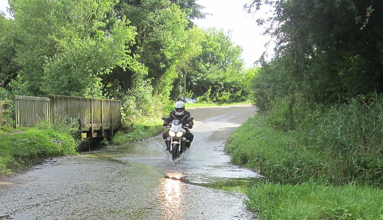 sl splashes through a small shallow ford on his street triple