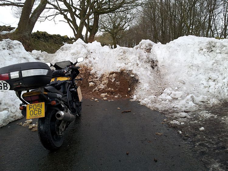 a thick wall of snow on a lancashire lane blocks the path to Ren's motorcycle