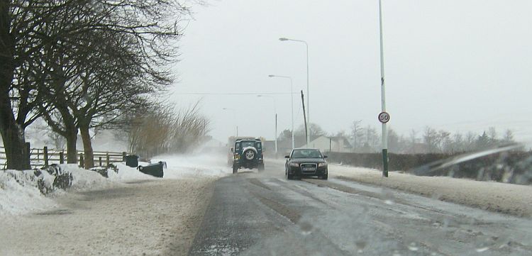 Snow drifts across an wintry road
