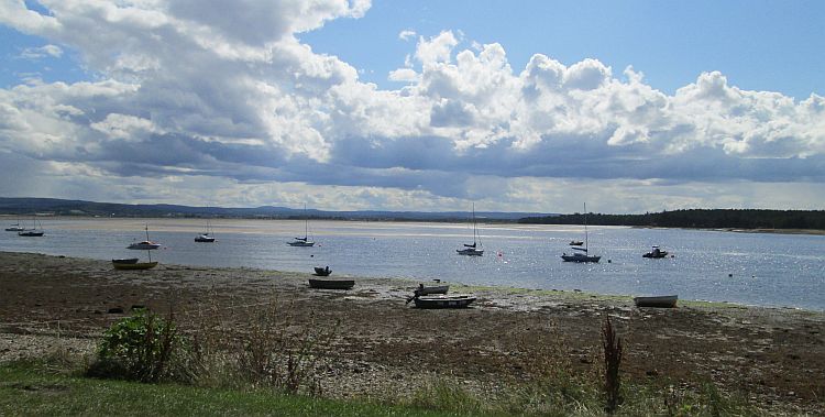 the broad sun filled bay at findhorn with boats by the sandy shoreline