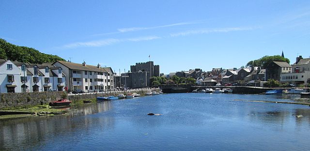 castletown harbour with the castle at the far end. boats, water, modern and old buildings.