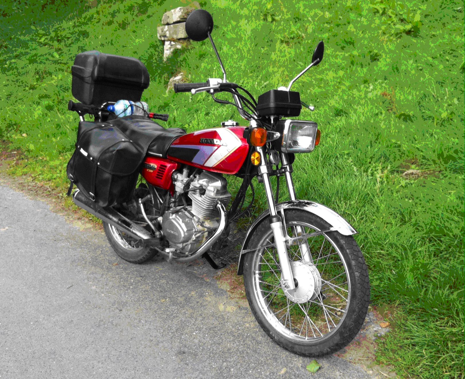 A classic Honda CG 125 in red complete with top box and saddle bags for touring