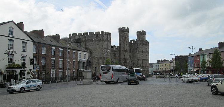 Caernarfon Castle dominates the end of a large open area surrounded by local shops
