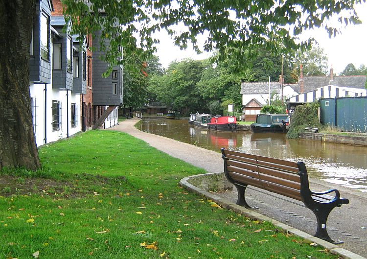 a canal winds its way through modern houses and older buildings in worsley
