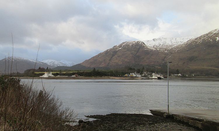 the small corran ferry is on the far side of the loch and snow on the hills
