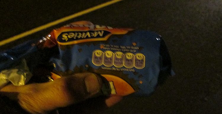 a packet of hob nobs in the hand on a darnk night in the street