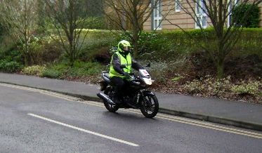 hugo riding along the road on his bike, all kitted up and with bright jacket