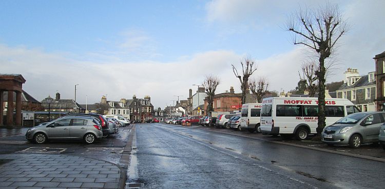 Moffat town centre. A broad street with parked cars and various shops