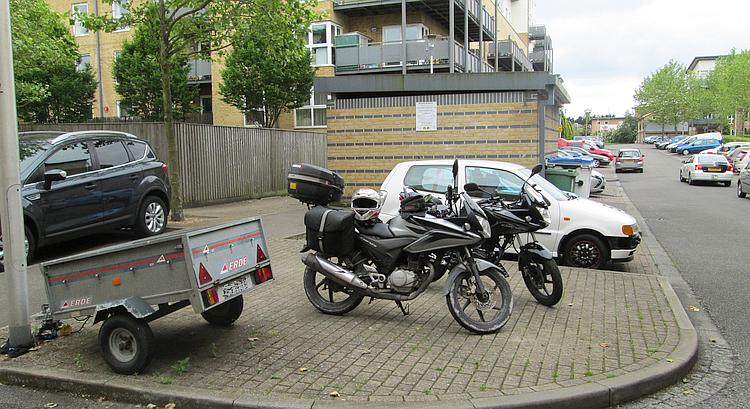 two motorcycles parked on the street near some flats