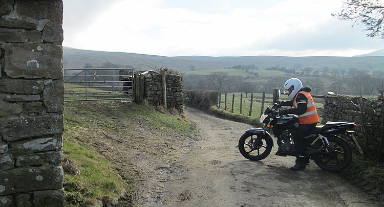 Sharon on her Keeway 125 turns around carefully in a narrow lane behind a farm
