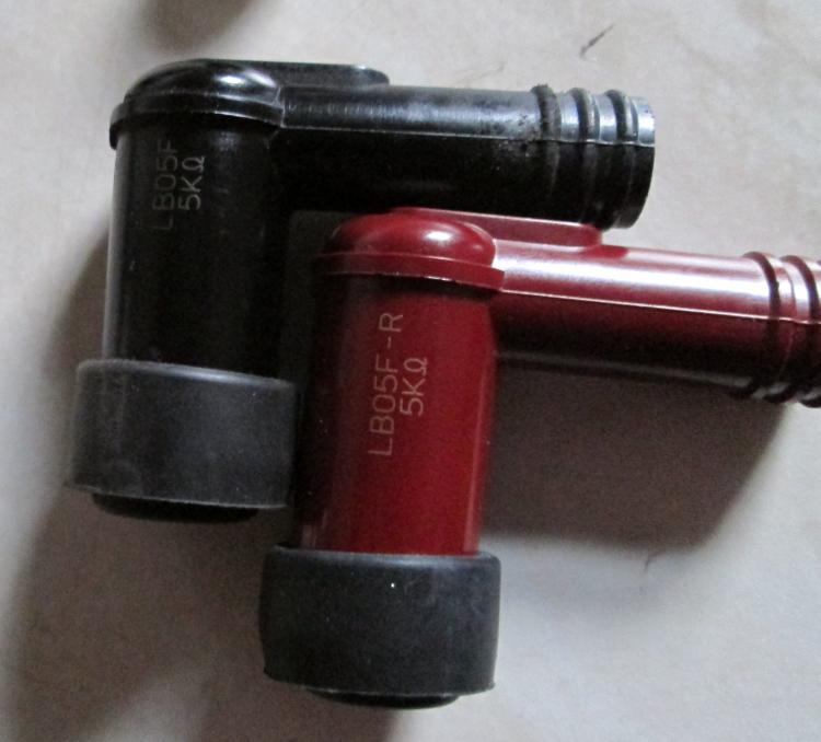 The old black and new red spark plug caps side by side