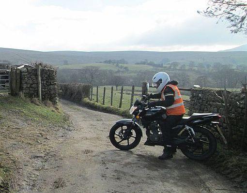 Sharon battles with her 125 on a narrow farm track in the lake district