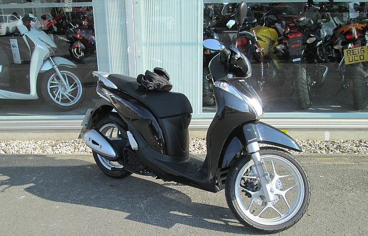 Honda's SH125i side view outside the shop. A simple scooter