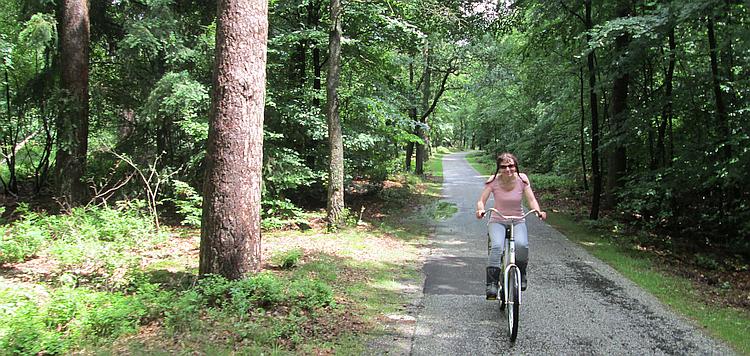 Sharon rides the white cycle through the trees - wearing her motorcycle boots!