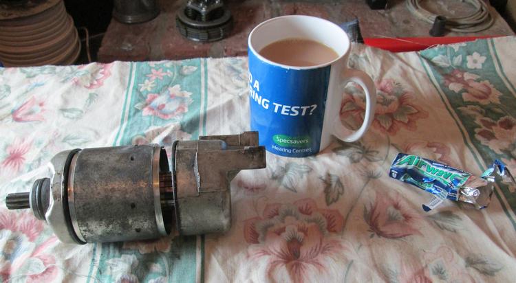 A starter motor in bits with a cup of tea and some chewing gum