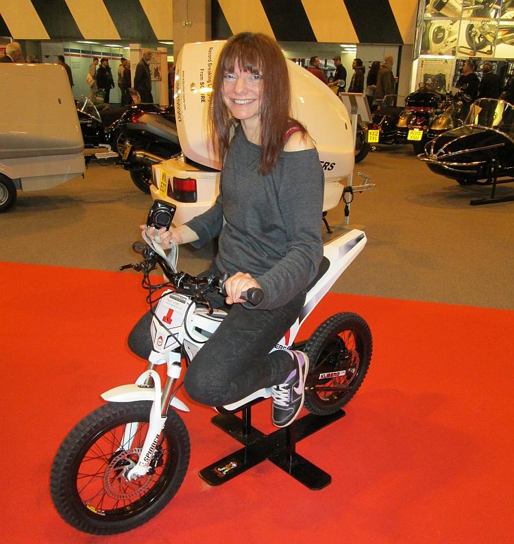 Sharon sits smiling on a tiny kids electric off road motorcycle