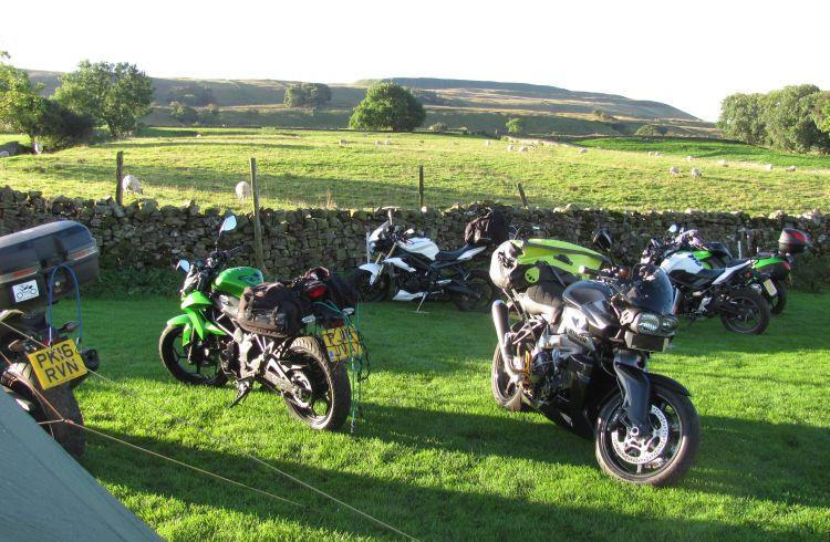 several motorcycles in a field with tents and campers