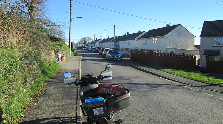 An ordinary street with houses, telephone poles, parked cars and hedges in St Austell