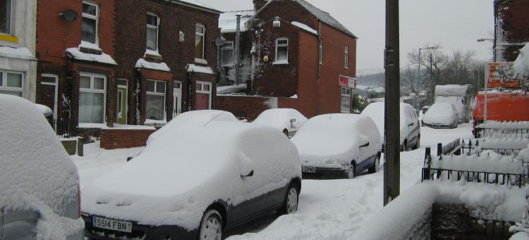Snow covered cars, street and houses on a terraced street