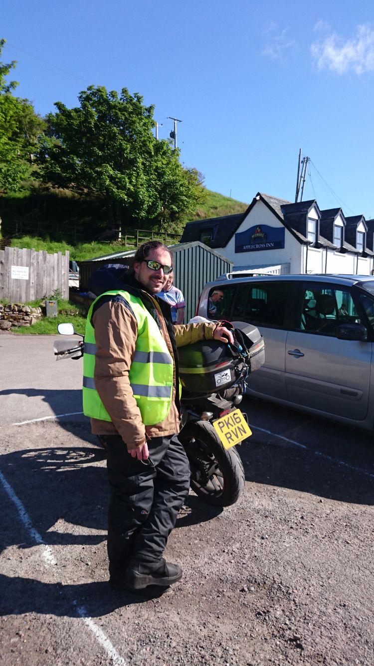 Ren stands next to his 500 smiling in the sun at the Applecross Pub