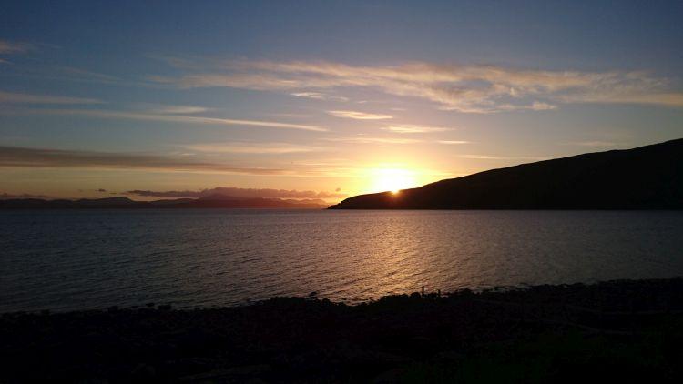 The sun set over a peninsula from the sea wall at Applecross. Deep red sunset