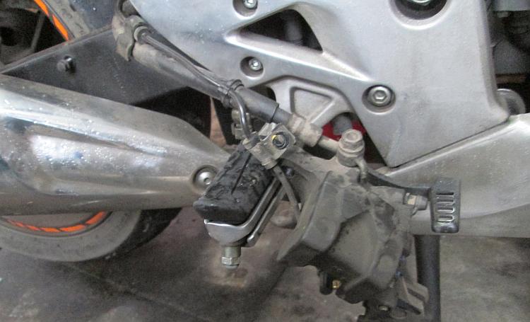 The rear brake calliper hangs over the footpeg and out of the way